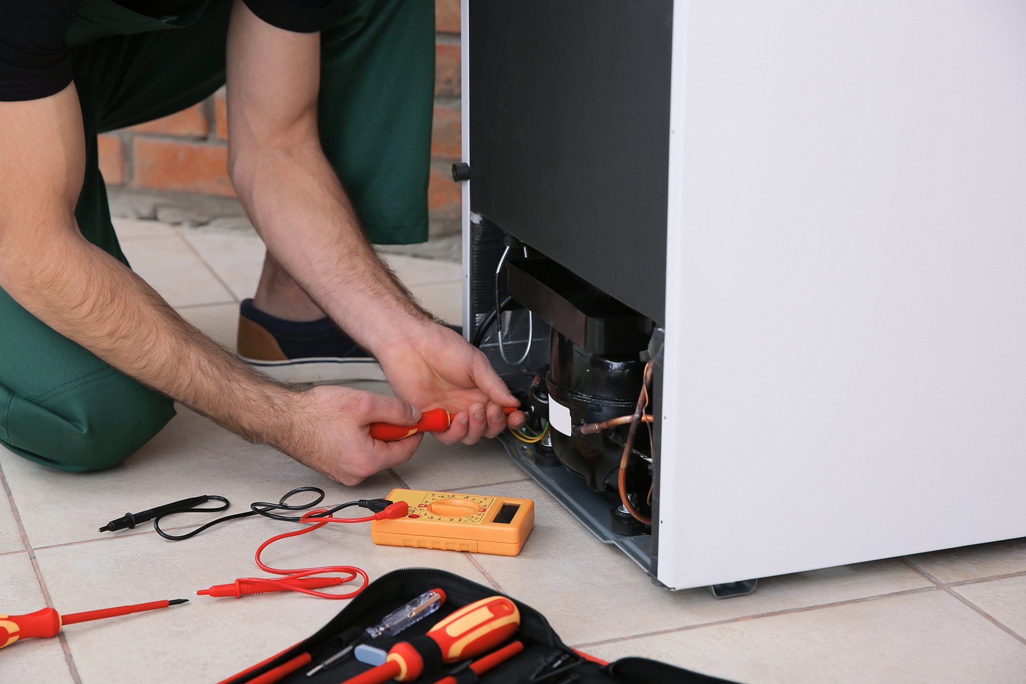 Male technician repairing broken refrigerator indoors, closeup