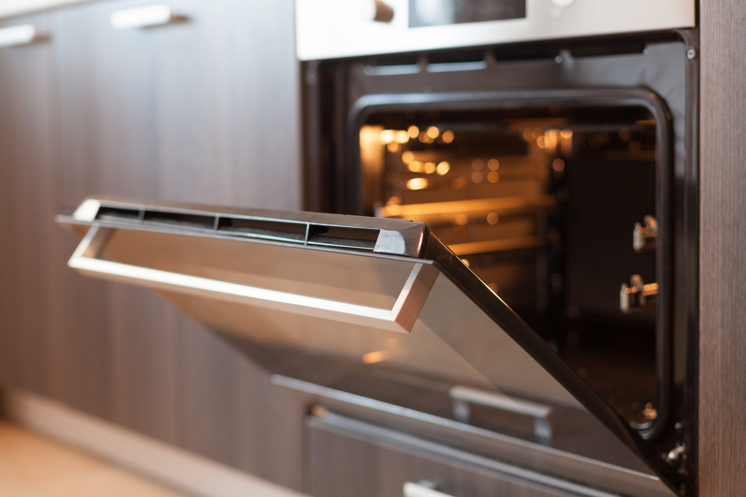 Empty open electric oven with hot air ventilation. New oven. Door is open and light is on.